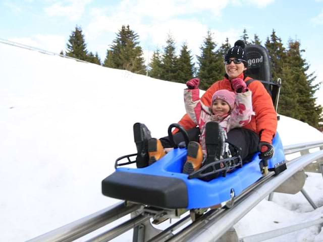 Enfant et son animatrice de colonie de vacances faisant de la luge mountain twister