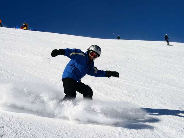 enfant faisant du snowboard en colonie de vacances d'hiver