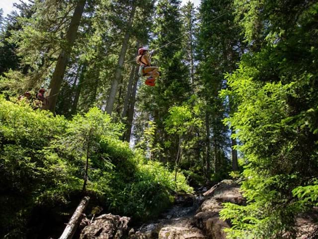 ado faisant de la tyrolienne en colo à la montagne