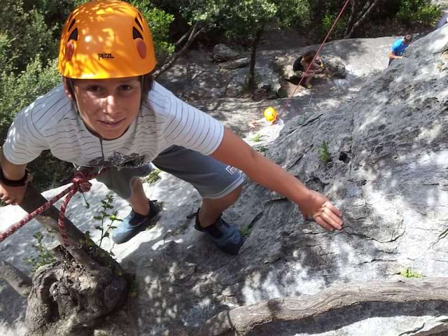 Portrait d'un preado sur la roche faisant de l'escalade en colonie 