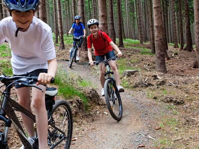 preados en colonie de vacances en forêt faisant une  randonnée à vélo 