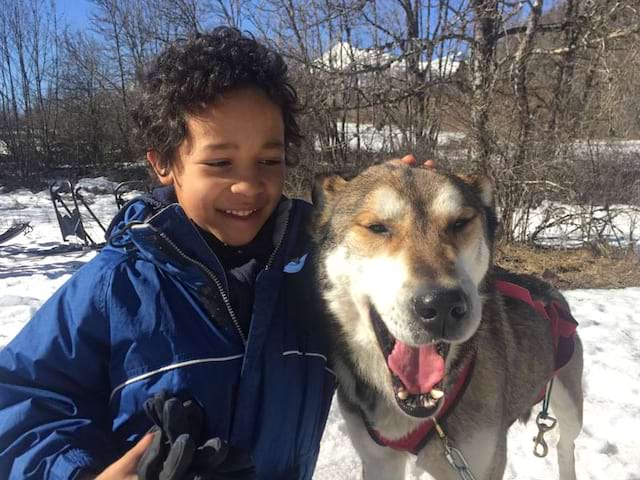 Portrait d'un enfant avec un chien de traineau en colo 