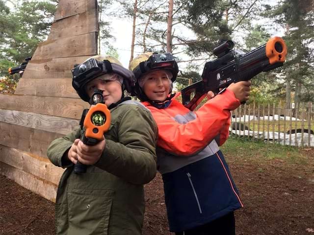 Deux jeunes qui font du laser game extérieur lors de leur colonie de vacances de l'automne