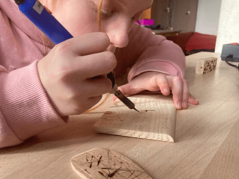 Jeune fille concentrée sur sa création durant l'activité pyrogravure en colo de vacances Equitation cet automne