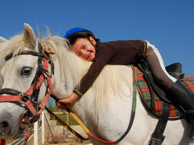 Jeune garçon qui profite de sa colonie de vacances Equitation de cet automne