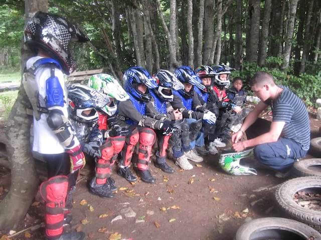 Groupe d'enfants avec équipement de moto suivant une formation sur la motocross en colonie de vacances