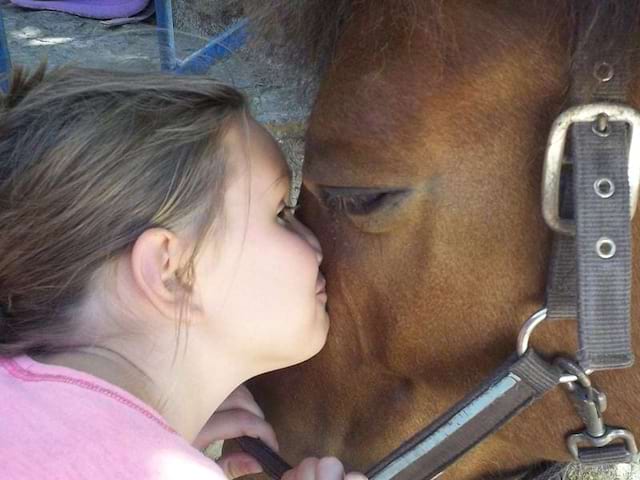 Fillette faisant un bisou à un poney