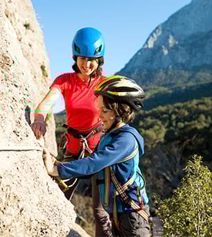 Enfant et animatrice de colo faisant de la via ferrata