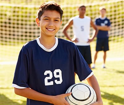 Ado jouant au football en colonie de vacances sportive cet été