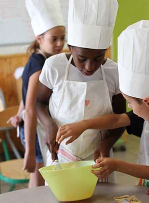 Enfants cuisinant ensemble en colonie de vacances à la toussaint