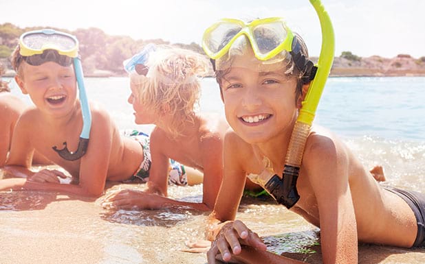 Groupe de jeunes enfants en bord de mer avec masque et tuba