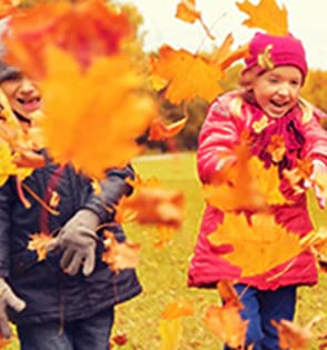 Enfants jouant avec les feuilles d'arbre de l'automne lors des colonies d'automne Djuringa