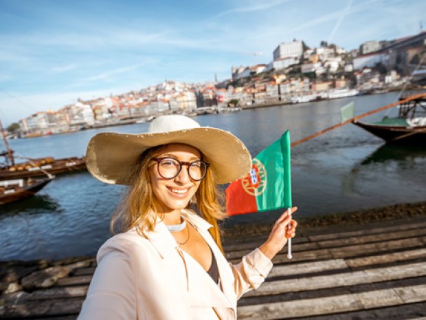 femme tenant un drapeau du portugal avec vue sur porto 