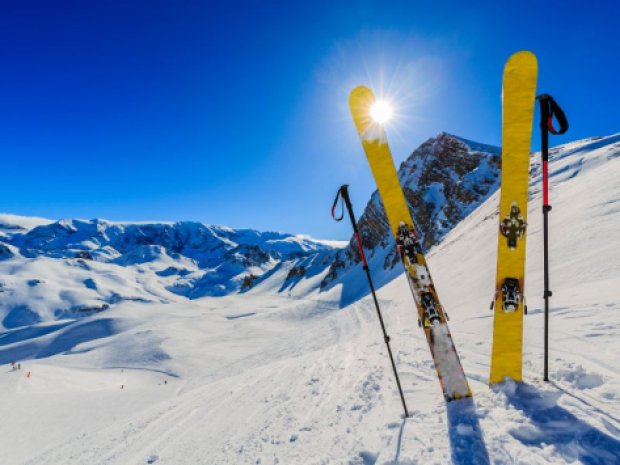 Environnement enneigé avec des skis autour du chalet où logent les jeunes hébergés en colo de vacances cet hiver