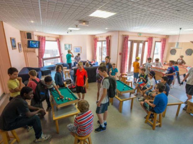 Enfants en colonie de vacances jouant dans la salle d'activité du centre de vacances à la montagne