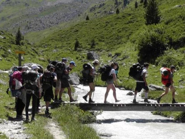 Ados en randonnée passant sur un petit ponton pour traverser un cours d'eau