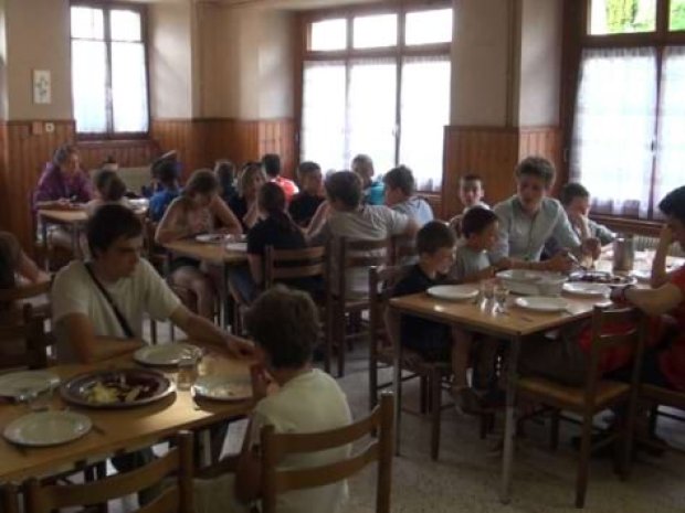 Jeunes de colonie de vacances en train de manger dans le chalet en hiver