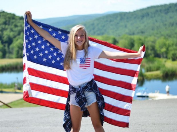 Centre de colonie de vacances avec une ado qui tient le drapeau américain derrière elle
