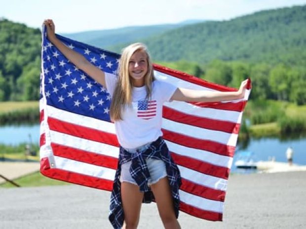 Centre de colonie de vacances avec une ado qui tient le drapeau américain derrière elle