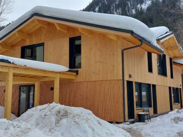 Vue sur la façade du bâtiment en bois rénové au centre de colo de vacances d'hiver de la Chaudane