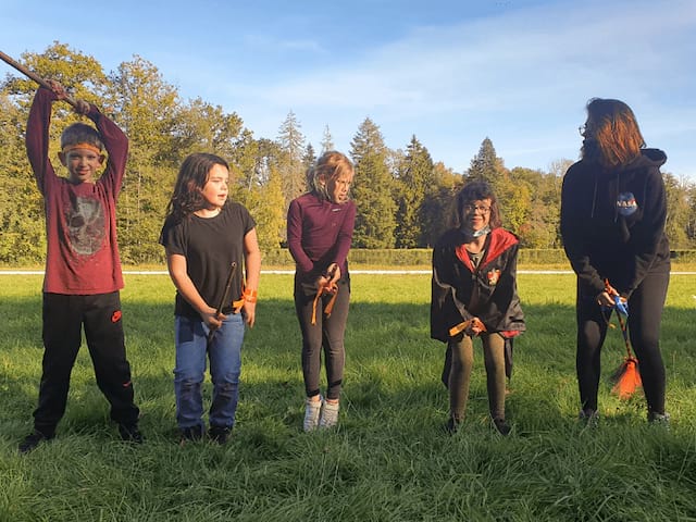 Groupe d'enfants qui joue aux sorciers dans les champs durant leur colo du printemps
