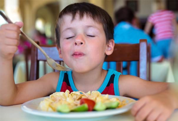 Enfant qui se régale avec les plats de la colo