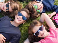 Enfants et ados dans l'herbe heureux, portant des lunettes de soleil