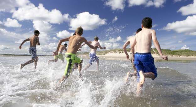 Groupe de pré-adolescents en train de courir dans la mer