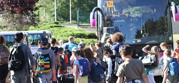 Groupe d'enfants s'appretant à partir en colonie de vacances en bus