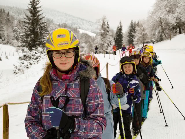 Groupe de jeunes en ski qui profitent de leur colo cet hiver