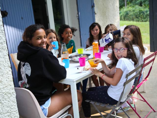 Enfants qui passent un bon moment ensemble lors du petit déjeuner en colo de vacances cet été