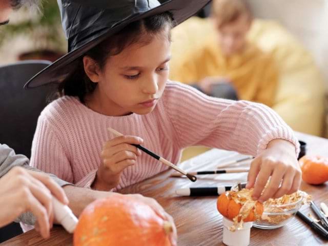 Jeune fille qui décore une citrouille lors de sa colo de vacances de cet automne