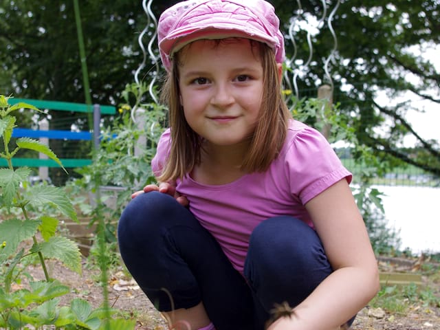 Fillette apprenant à jardin en colonie de vacances à la ferme