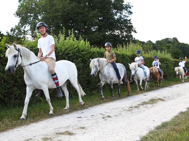 Enfants à cheval en colonie de vacances à la ferme cet été