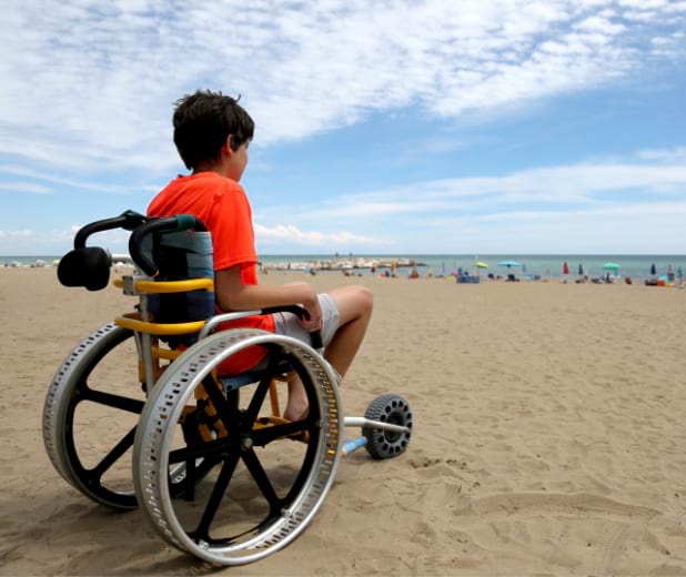 Enfant en situation de handicap moteur à la plage en colonie de vacances