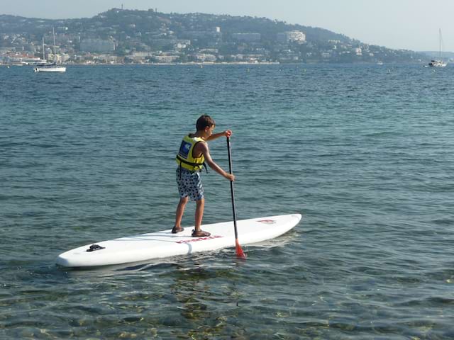 Enfant de 12 ans faisant du stand up paddle en colonie de vacances à la mer
