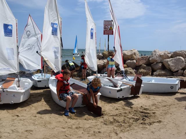 Groupe d'enfants sur la plage s'apprêtant à faire de l'optimist en colonie de vacances