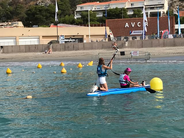 Jeune fille apprenant à faire du stand up paddle en colonie de vacances à la mer