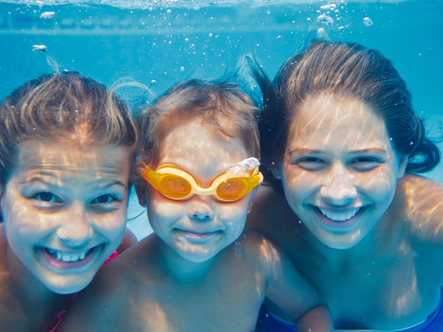 Trois enfants sous l'eau dans la piscine en colonie de vacances d'ét