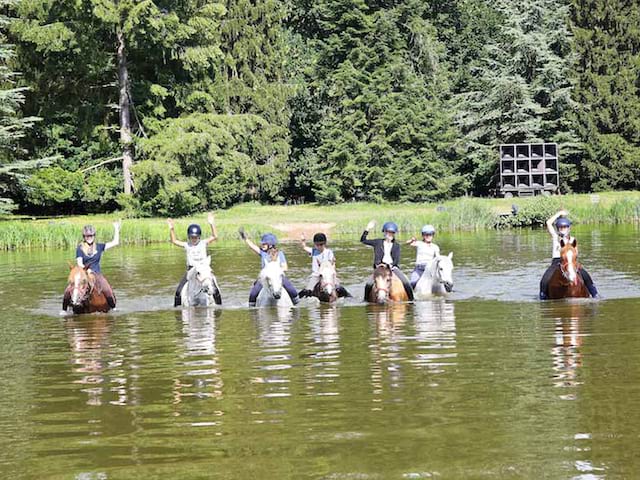 Enfants traversant la rivière à cheval en colonie de vacances moyen age