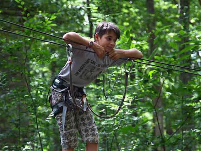 ado faisant de l'accrobranche en colonie de vacances cet été