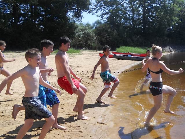 groupe d'ados courant dans l'eau en colo cet été 