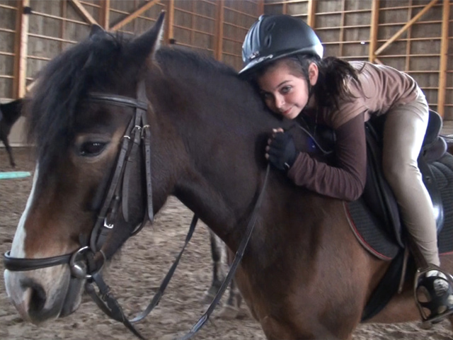 Fillette faisant un calin à son cheval en colonie de vacances
