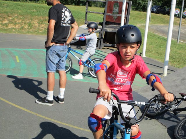 enfants apprenant à faire du bmx avec leur animateur de colonie de vacances