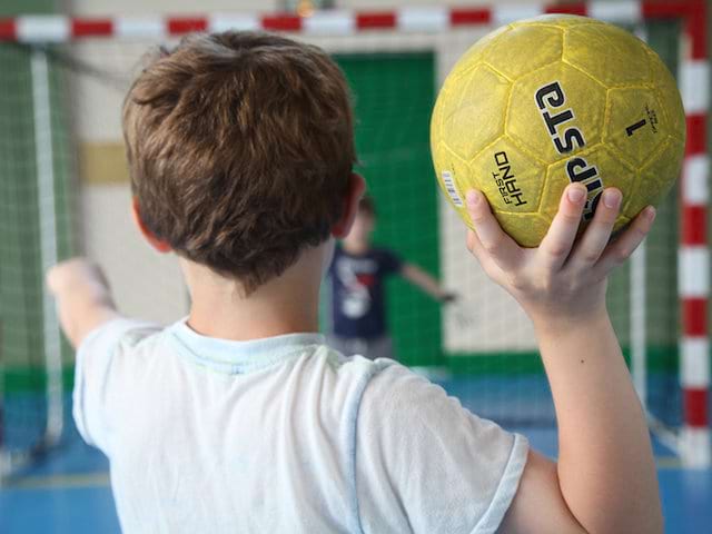 Enfant jouant au handball en colonie de vacances sportive