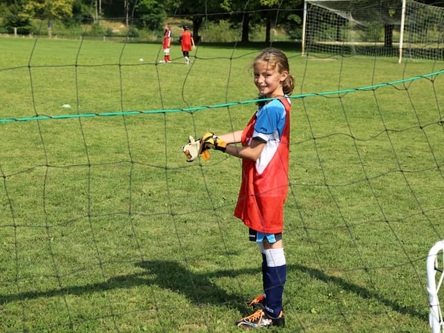 fillette jouant au football cet été en colonie de vacances sportives