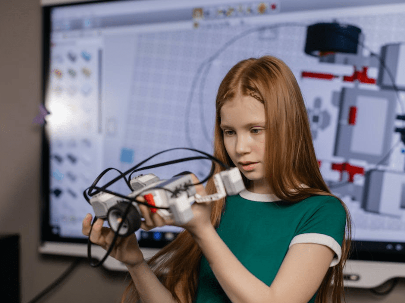 Jeune fille qui construit un objet en lego durant sa colo Construction Block de l'automne