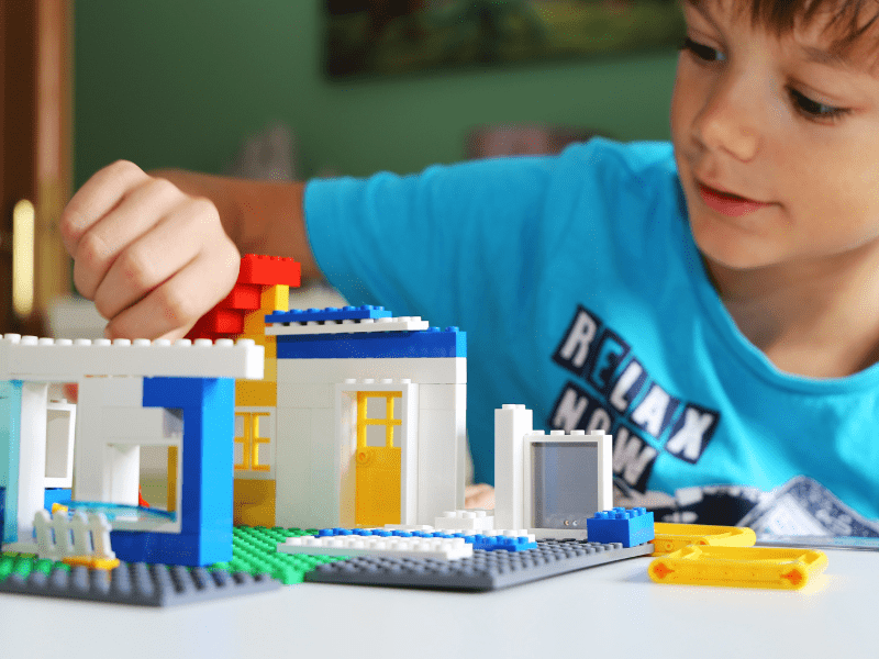 Jeune garçon qui s'amuse à assembler des legos en colonie de vacances cet automne