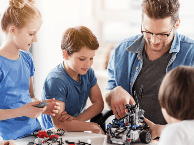 Groupe de jeunes qui s'amusent à des jeux de constructions en colo de vacances cet automne