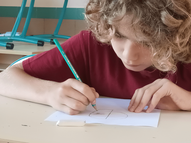 Jeune garçon qui dessine des dessins Manga en colo de vacances de la Toussaint